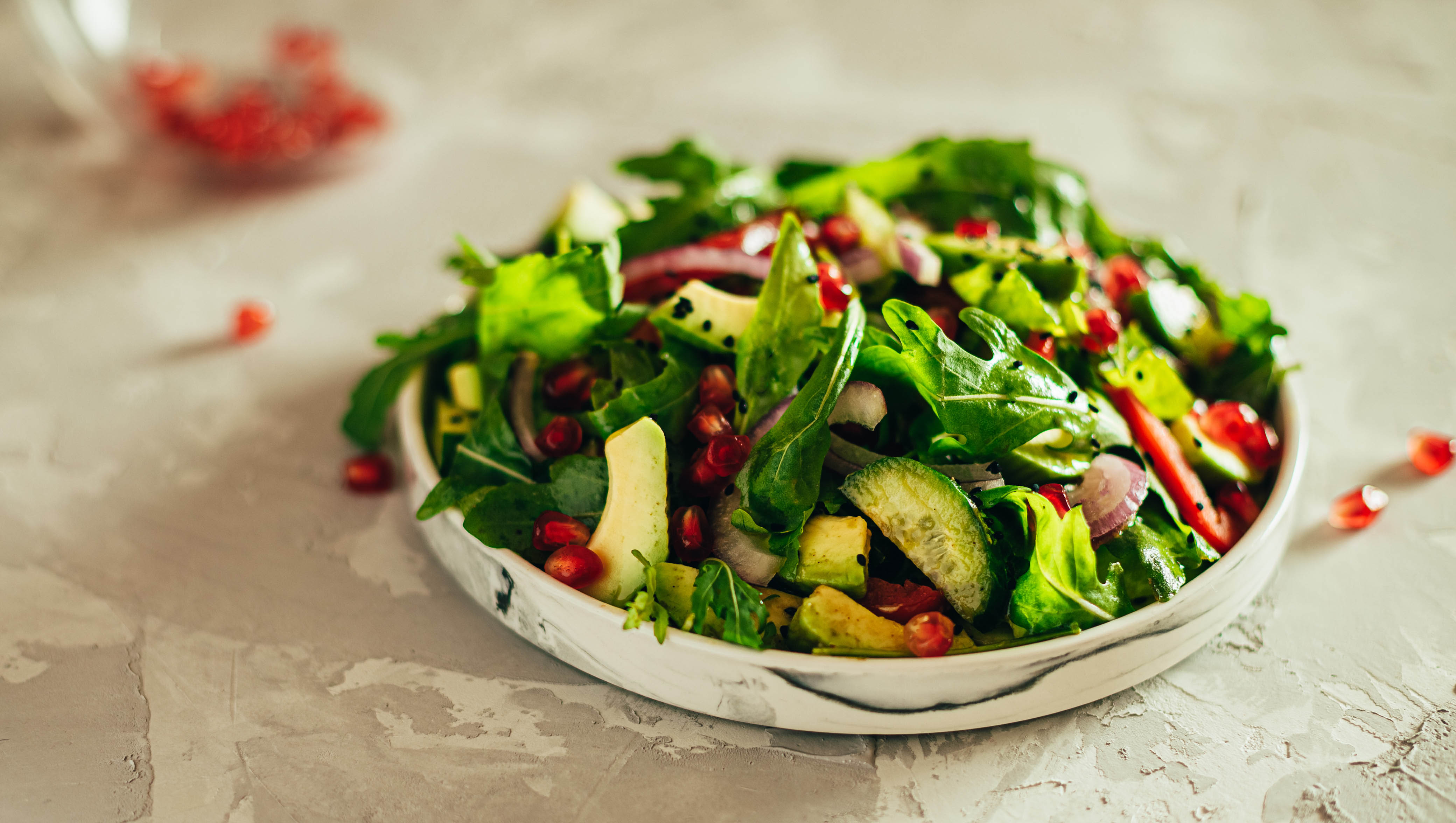 Close-up of greens and pomegranate salad with cucumbers and sesame seeds Close-up of greens and pomegranate salad with cucumbers and sesame seeds
